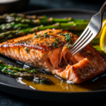 Golden-brown salmon steak with crispy skin, garnished with dill and lemon on a white plate.