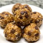 Chocolate peanut butter protein balls with oats and chocolate chips in a white bowl