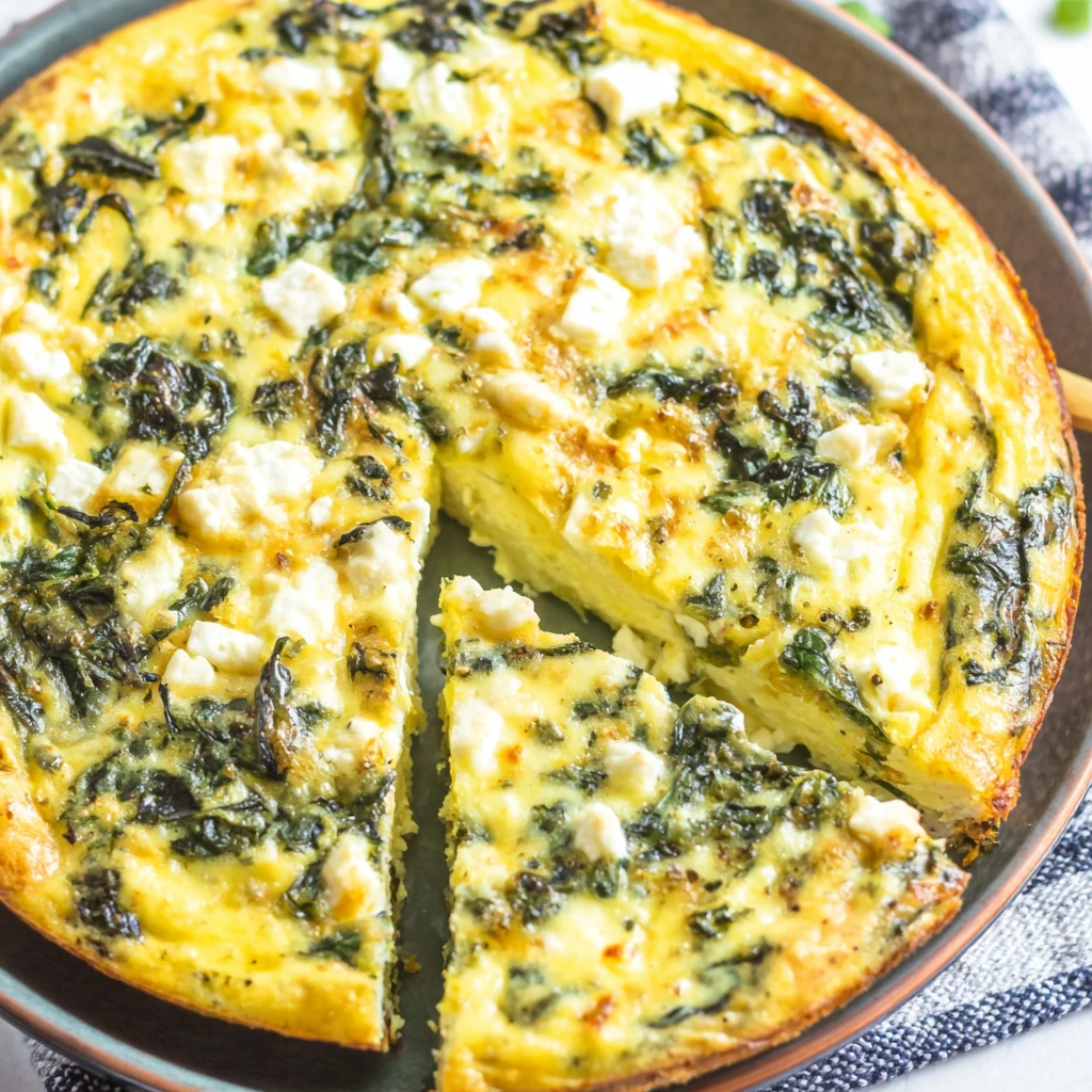 Crustless quiche feta spinach with golden egg base, spinach, and crumbled feta, sliced and served